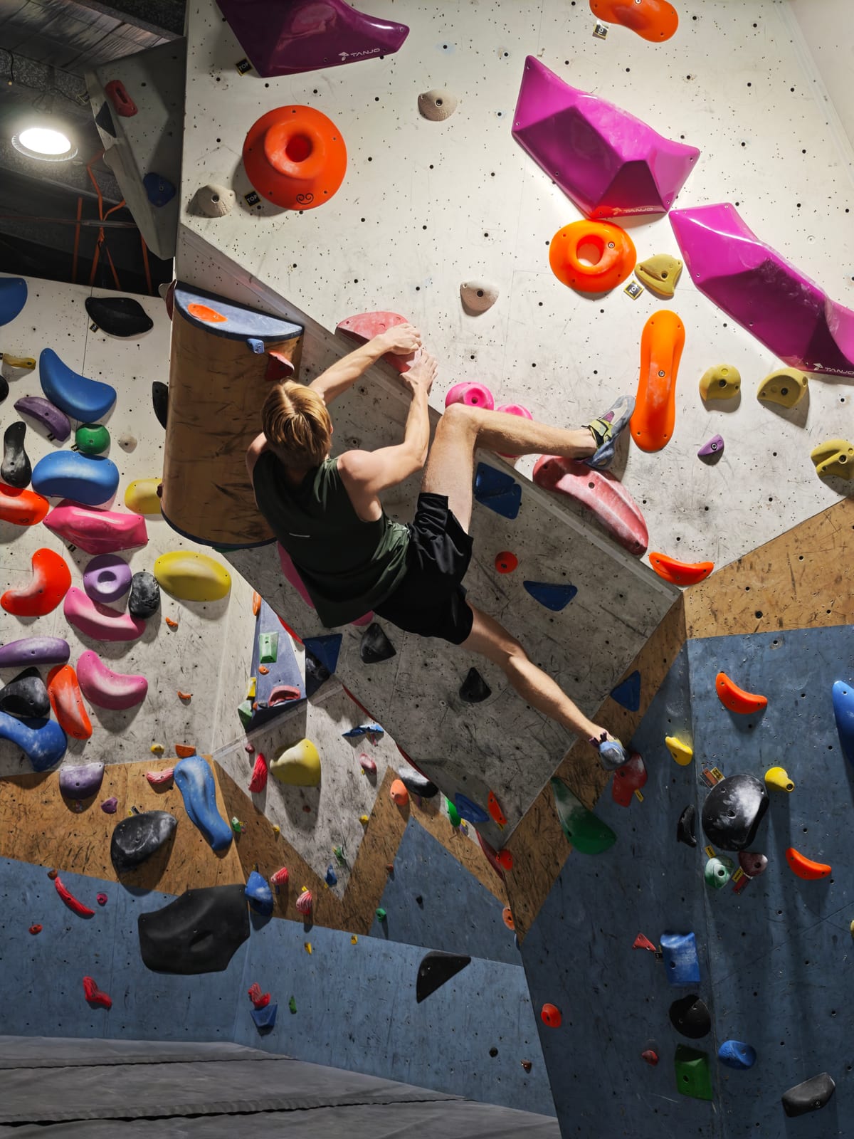 A climber attempting a technical boulder problem on colourful holds at Wall Walkers.